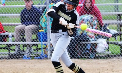 Woman swinging baseball bat on field.