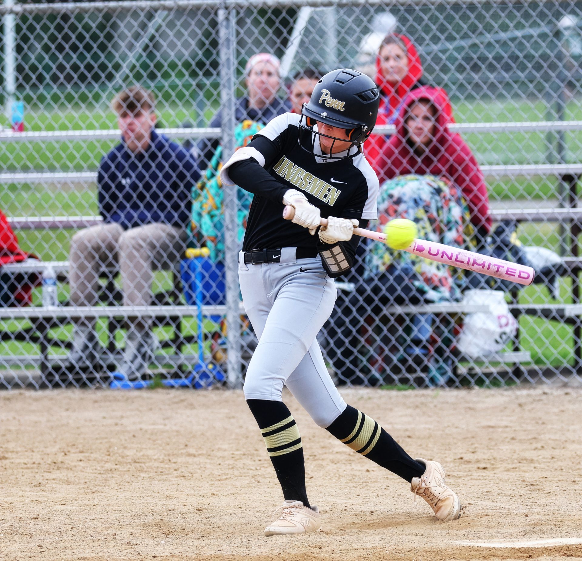 Woman swinging baseball bat on field.
