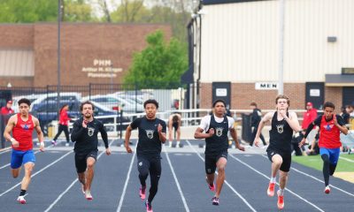 Athletes in uniforms running on a track.