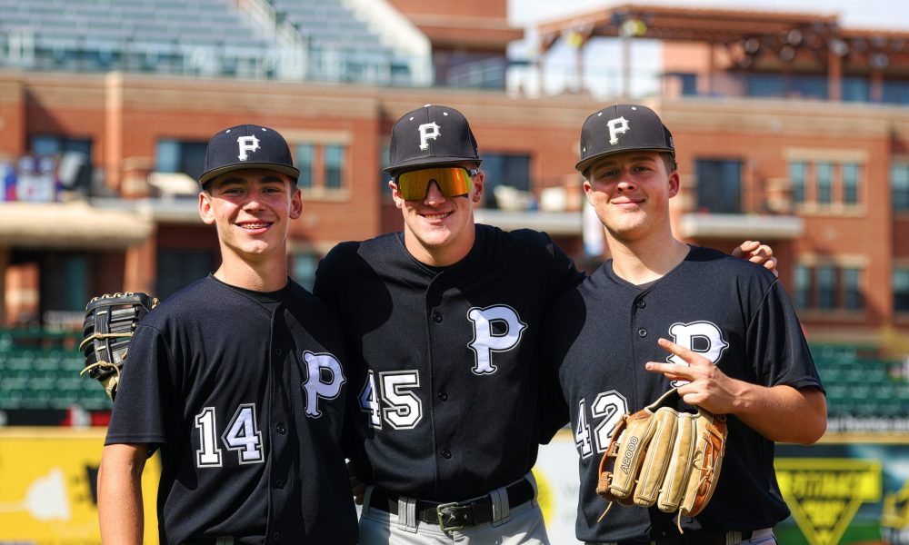 Three baseball players posing together on a field.