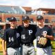Three baseball players posing together on a field.