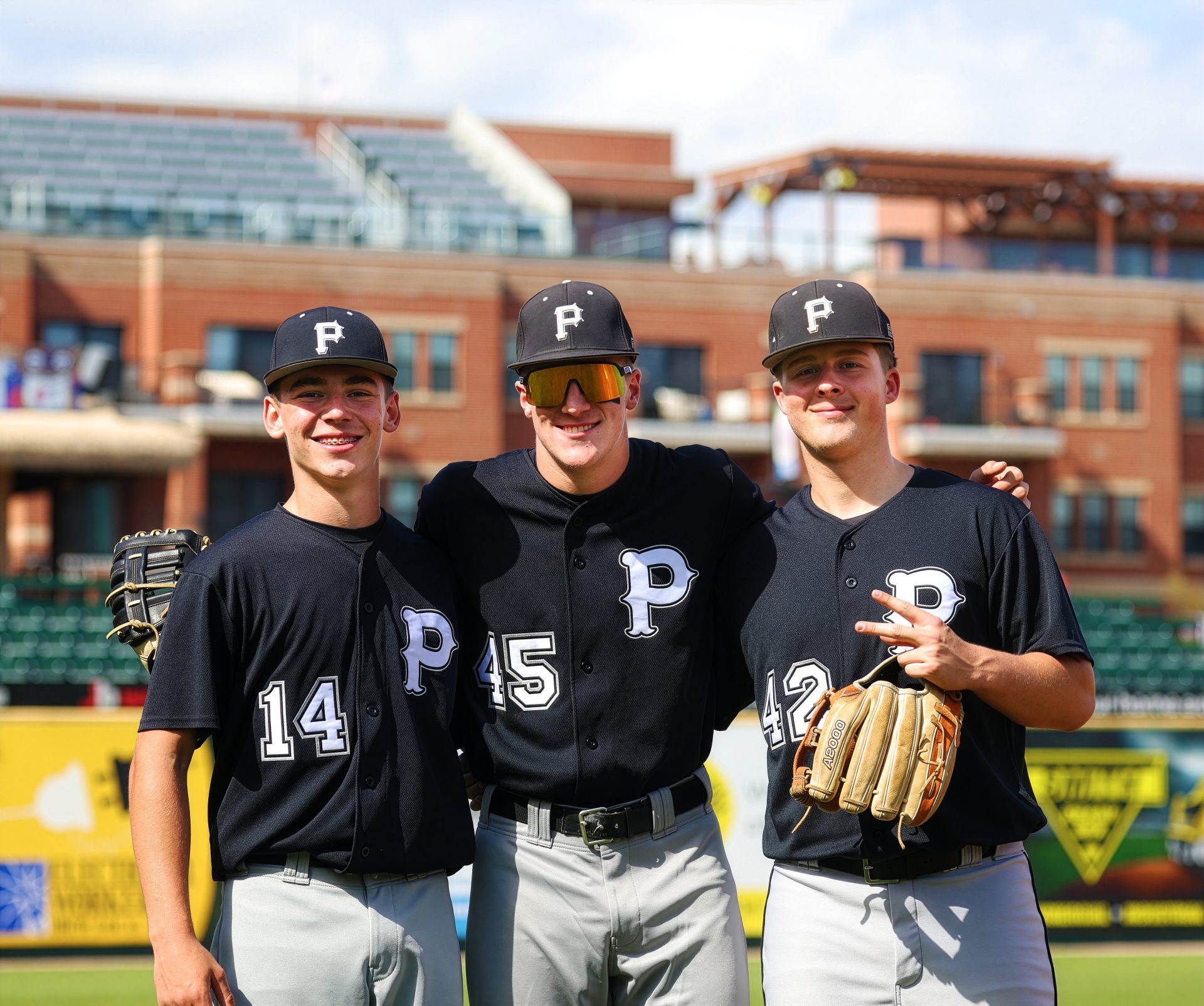 Three baseball players posing together on a field.
