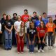 Group of people posing for a photo in front of a classroom.
