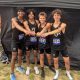 Four athletes posing together, celebrating their victory in a race.
