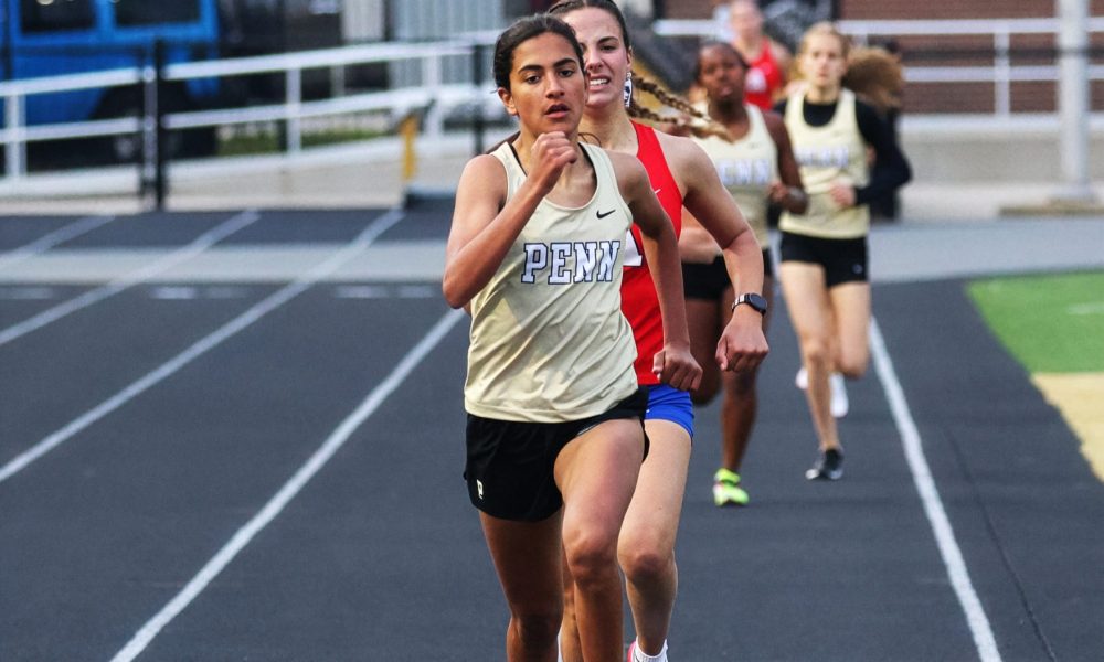 Female runner in yellow shoes leading a group of runners on a track.