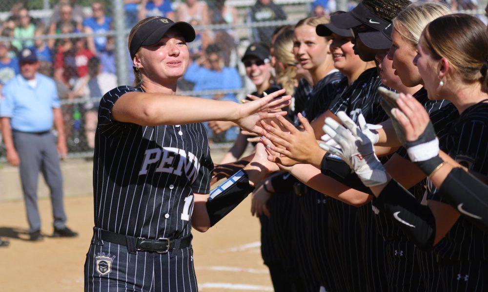 Woman in uniform receiving high fives from teammates after a game.