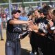 Woman in uniform receiving high fives from teammates after a game.