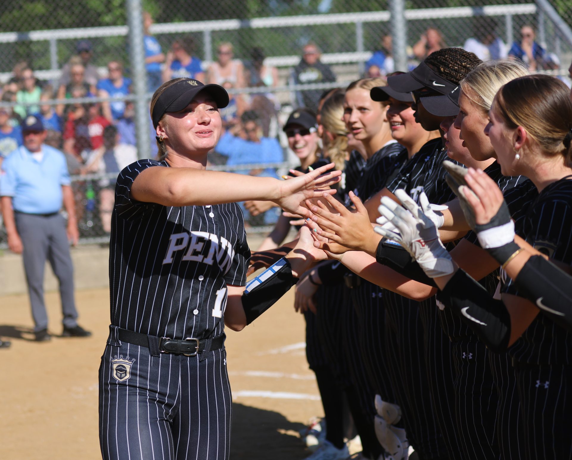 Woman in uniform receiving high fives from teammates after a game.
