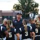 A football coach talks to a team on the field.