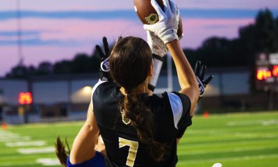 Woman in black and white uniform holding football.