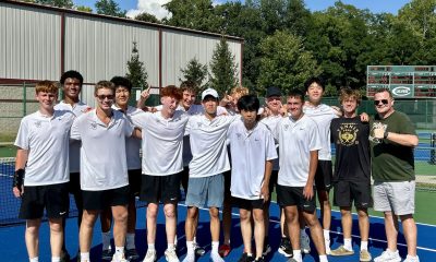 Boys tennis players pose for a photo on a tennis court.