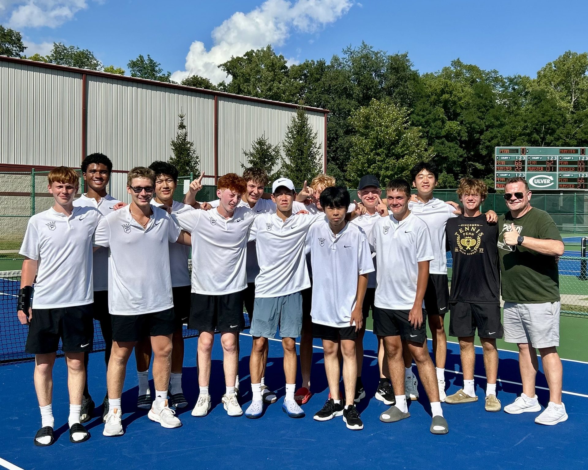 Boys tennis players pose for a photo on a tennis court.