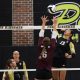A volleyball players jumps up to hit the ball.