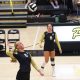 Two female volleyball players in action on a court.
