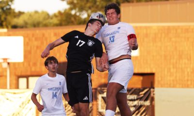 Two soccer players leap for the ball.