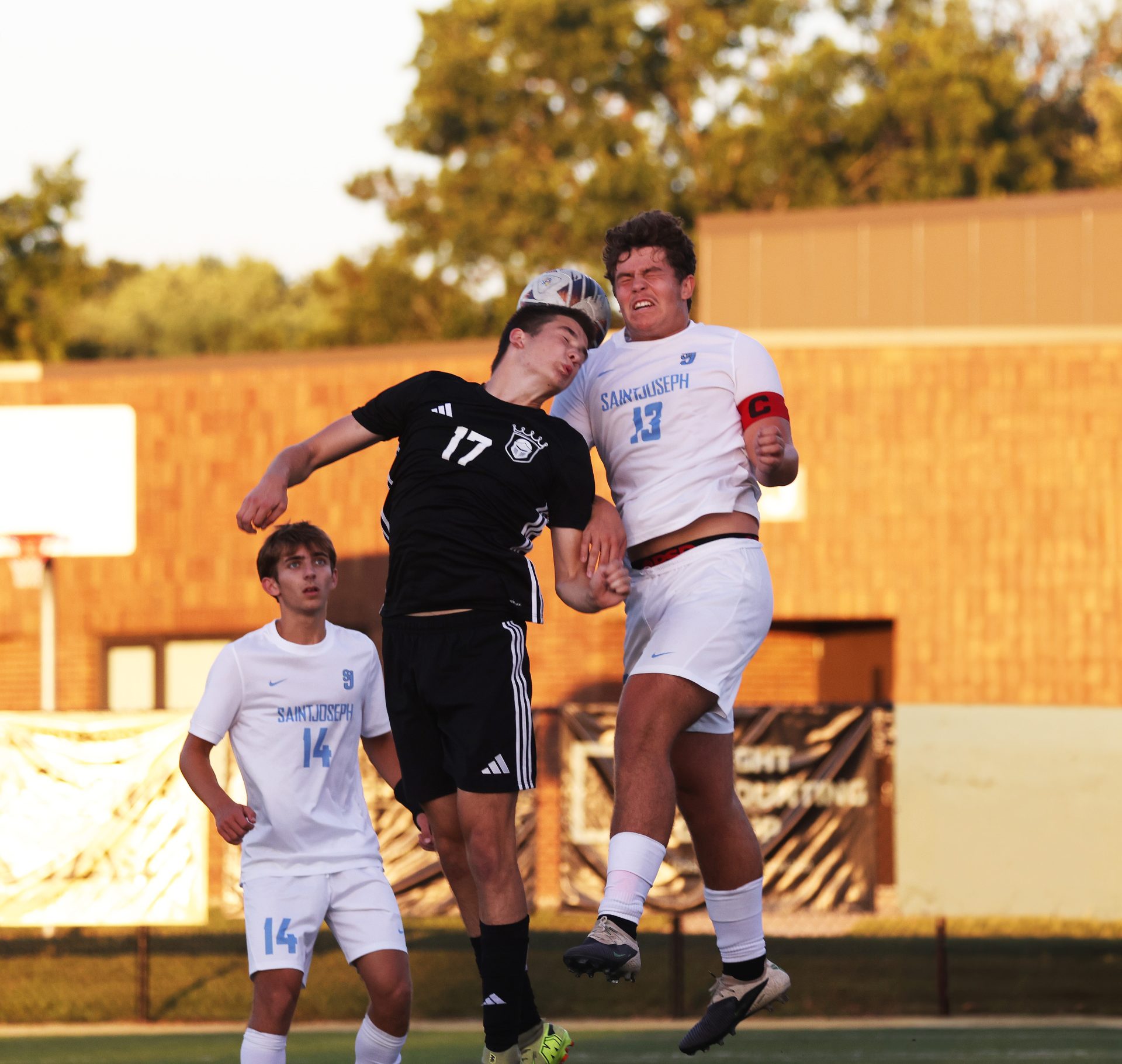 Two soccer players leap for the ball.