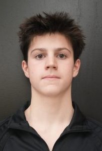A young man in a black and gold track suit.