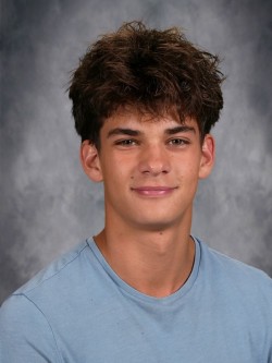 A young man with a short hairstyle, wearing a blue shirt, poses for a school portrait.