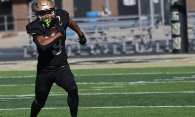 A football player runs on the field carrying a football.