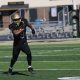 A football player runs on the field carrying a football.
