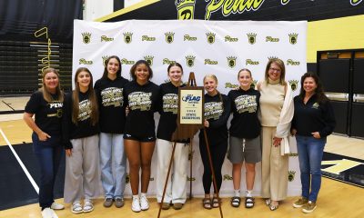 A group of young athletes posing for a photo with a trophy, a woman, and a man in a suit