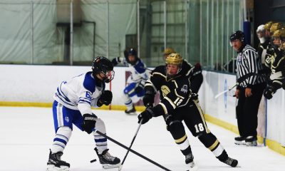 Two hockey players in mid-action on an ice rink, one in a blue jersey and the other in a
