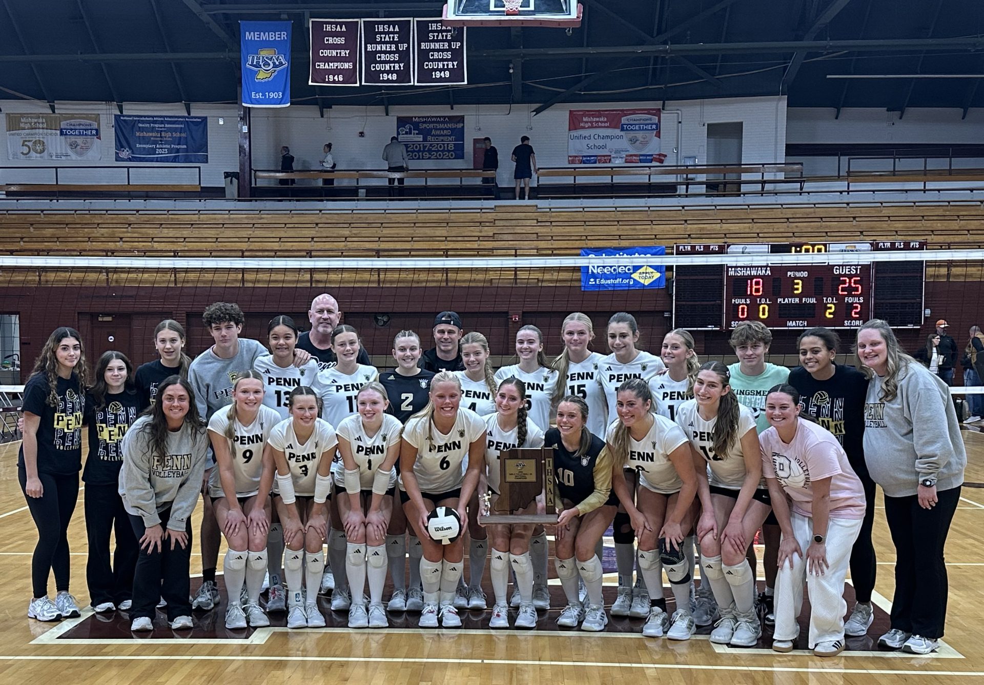 A group of female volleyball players posing for a team photo on a court.