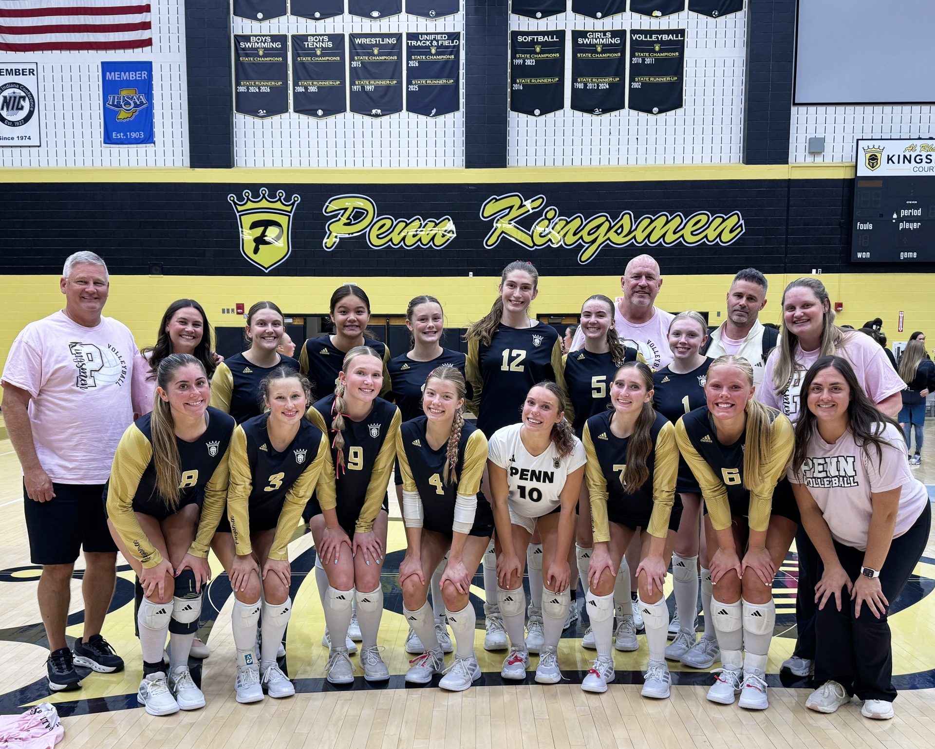 A group of young women in sports uniforms posing together for a team photo.